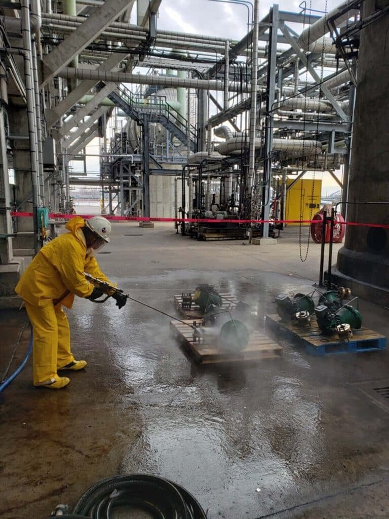 Workers cleaning factory floor with water jets